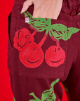 Close up of Madeline's hand in the back pocket of Paintstamped Work Pants in Cherry