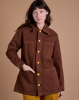 Alex is wearing a buttoned up Ripstop Field Coat in Fudgesicle Brown