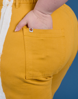 Close up of Ashley's hand in the back pocket of Painted Work Pants in Mustard Yellow