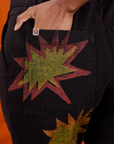Close up of Kandia's hand in the back pocket of Paintstamped Work Pants in Explosion