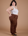 Side view of Carpenter Jeans in Fudgesicle Brown and Cropped Tank in Vintage Tee White on Ashley