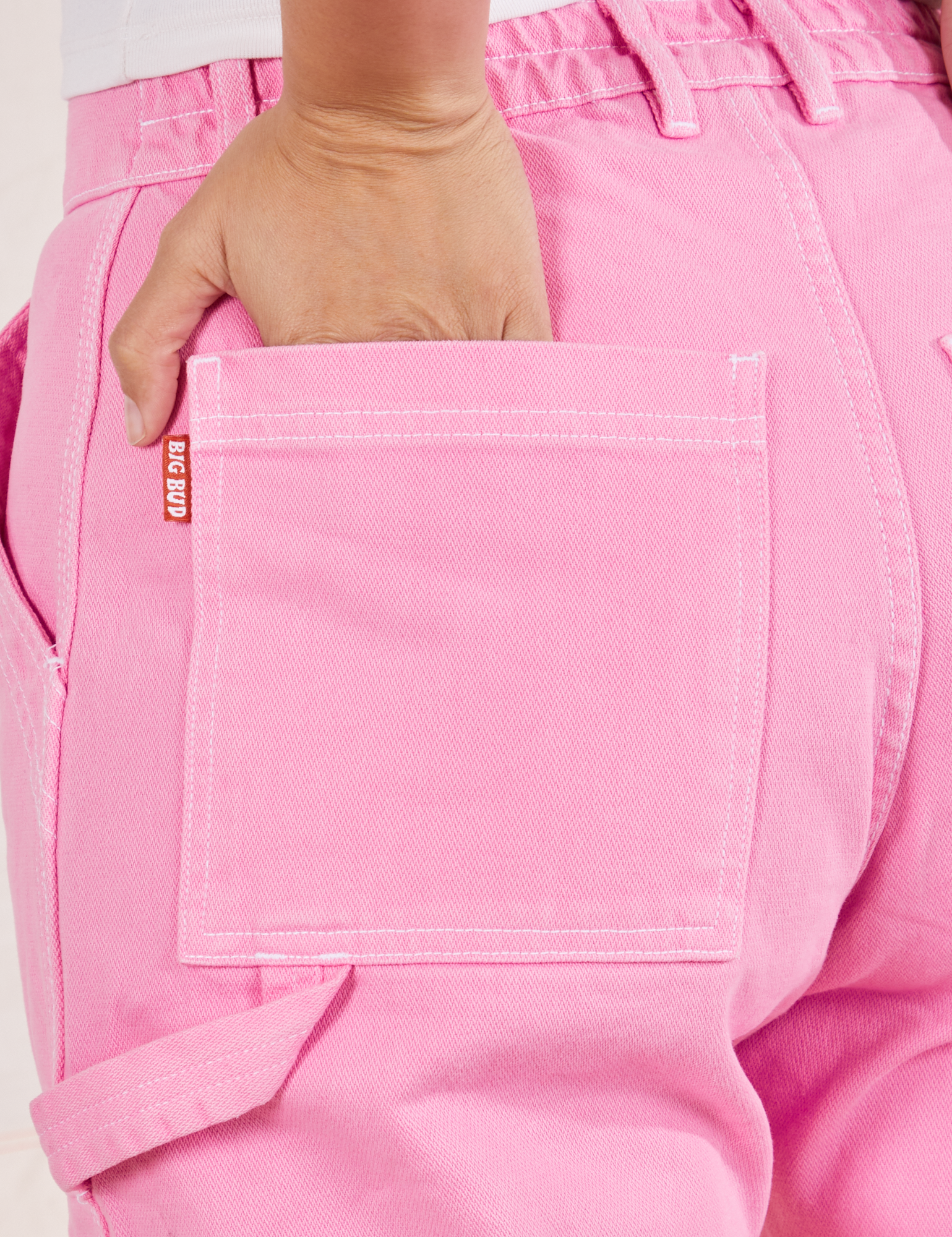 Carpenter Jeans in Bubblegum Pink back pocket close up. Tiara has her hand in the pocket.