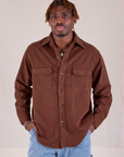 Isaac is wearing a buttoned up Flannel Overshirt in Fudgesicle Brown