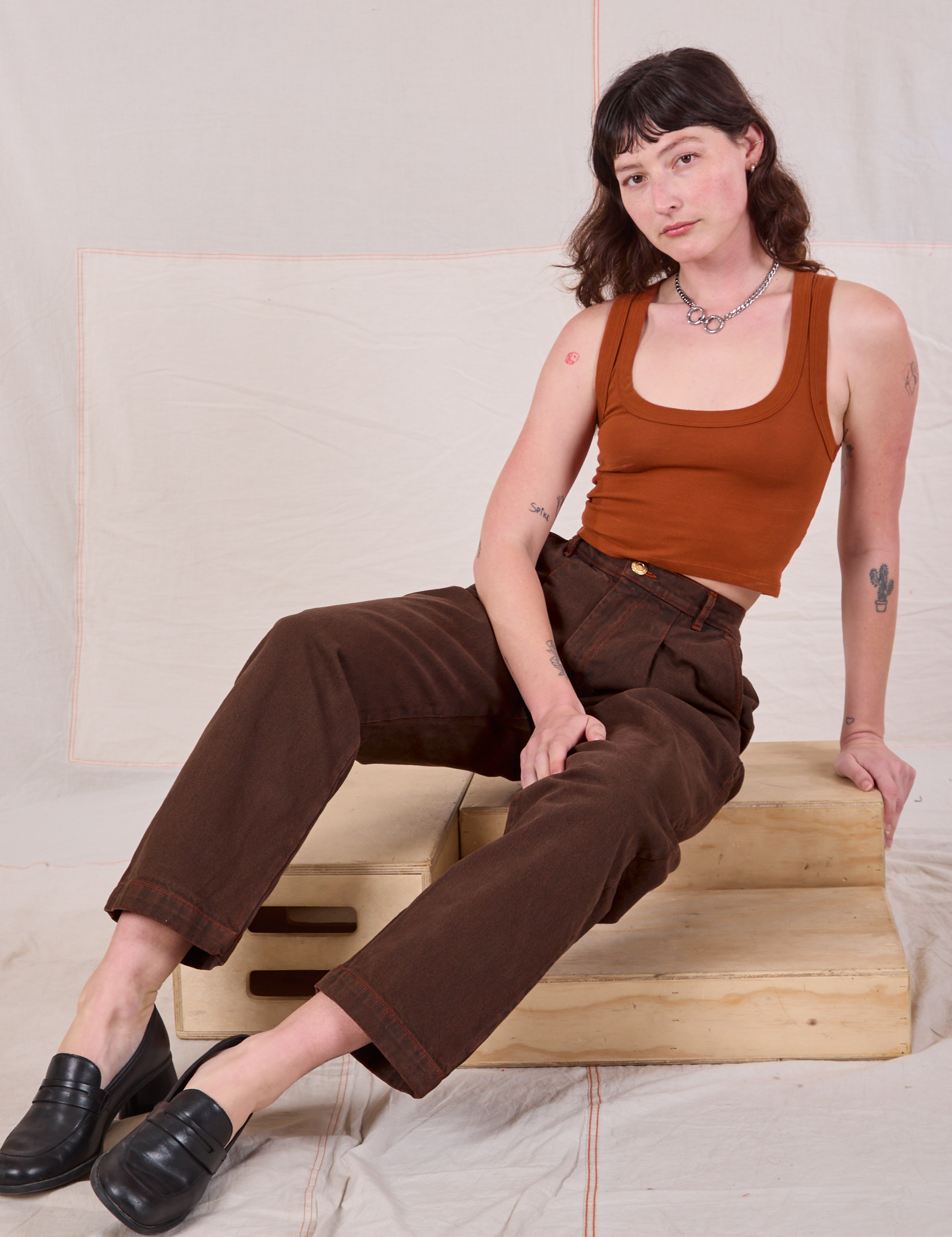Alex is wearing Overdyed Denim Trouser in Fudge and burnt terracotta Cropped Tank