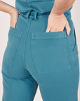 Back pocket close up of Heritage Short Sleeve Jumpsuit in Marine Blue. Tiara has both her hands in the pockets.