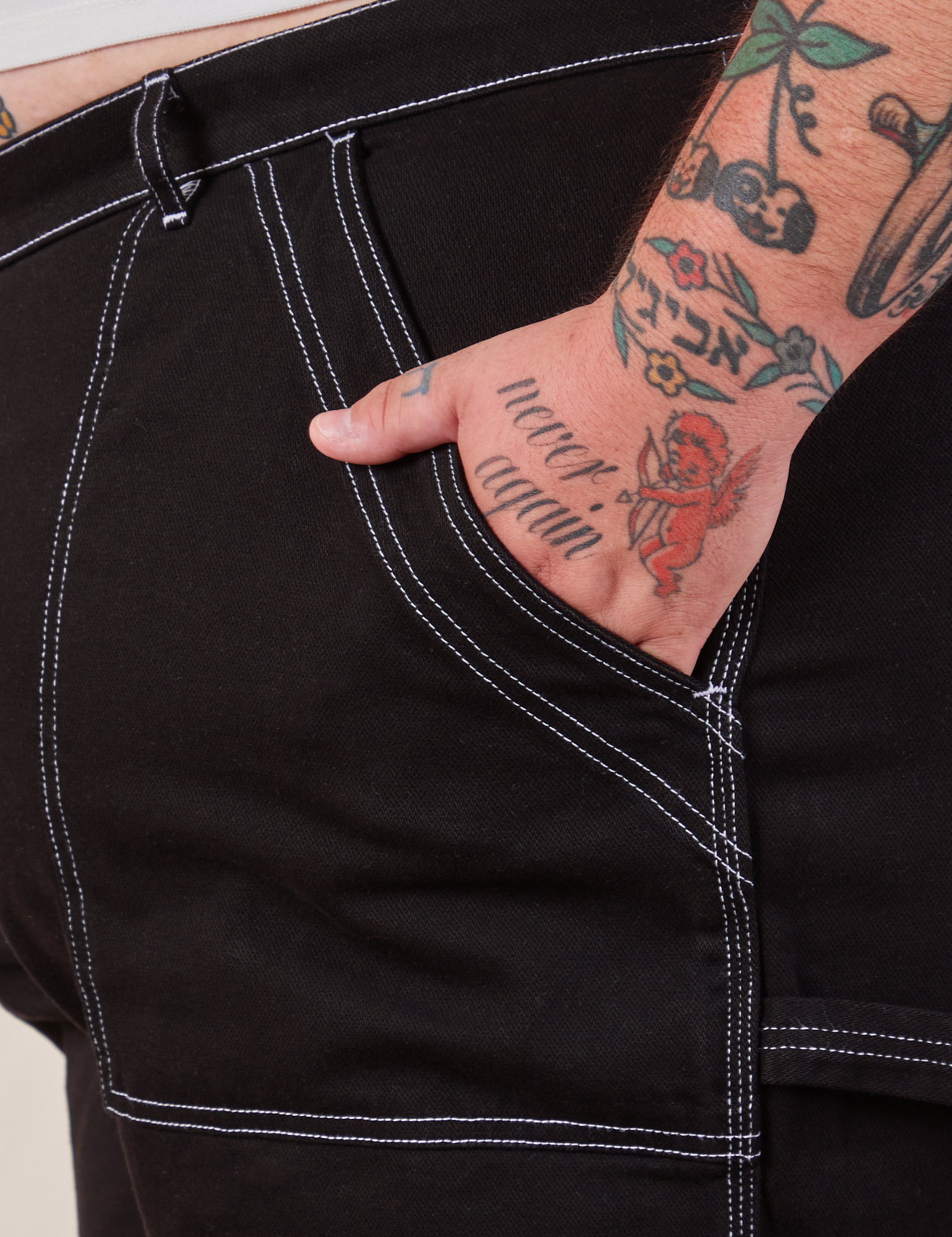 Carpenter Shorts in Basic Black front pocket close up. Sam has their hand in the pocket.