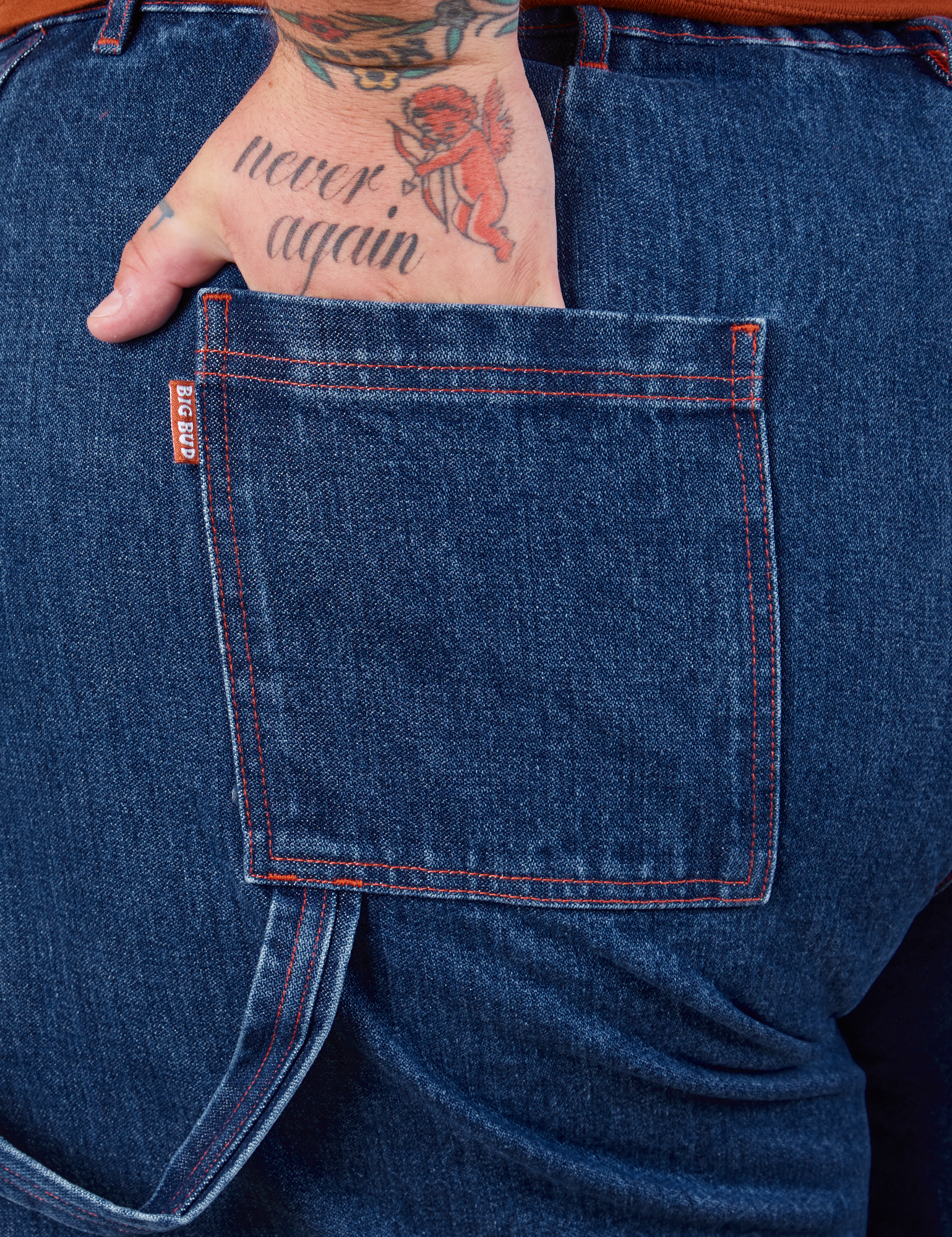 Carpenter Shorts in Dark Wash back pocket close up. Sam has their hand in the pocket.