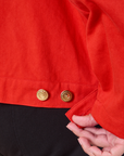Close up of custom brass buttons on the Mechanic Jacket in Mustang Red worn by Miguel