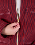 Mechanic Jacket in Mustang Red zipper close up. Marielena is pulling on the zipper tab.
