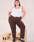 Marielena is 5'8" and wearing 2XL Railroad Carpenter Jeans in Fudgesicle Brown paired with vintage tee off-white Square Neck Tank