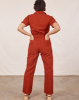 Back view of Short Sleeve Jumpsuit in Paprika. Tiara has both hands in the back pockets.