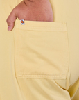 Close up of Miguel's hand in the back pocket of Short Sleeve Jumpsuit in Butter Yellow