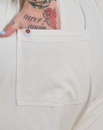 Close up of Sam's hand in the back pocket of Short Sleeve Jumpsuit in Vintage Tee White