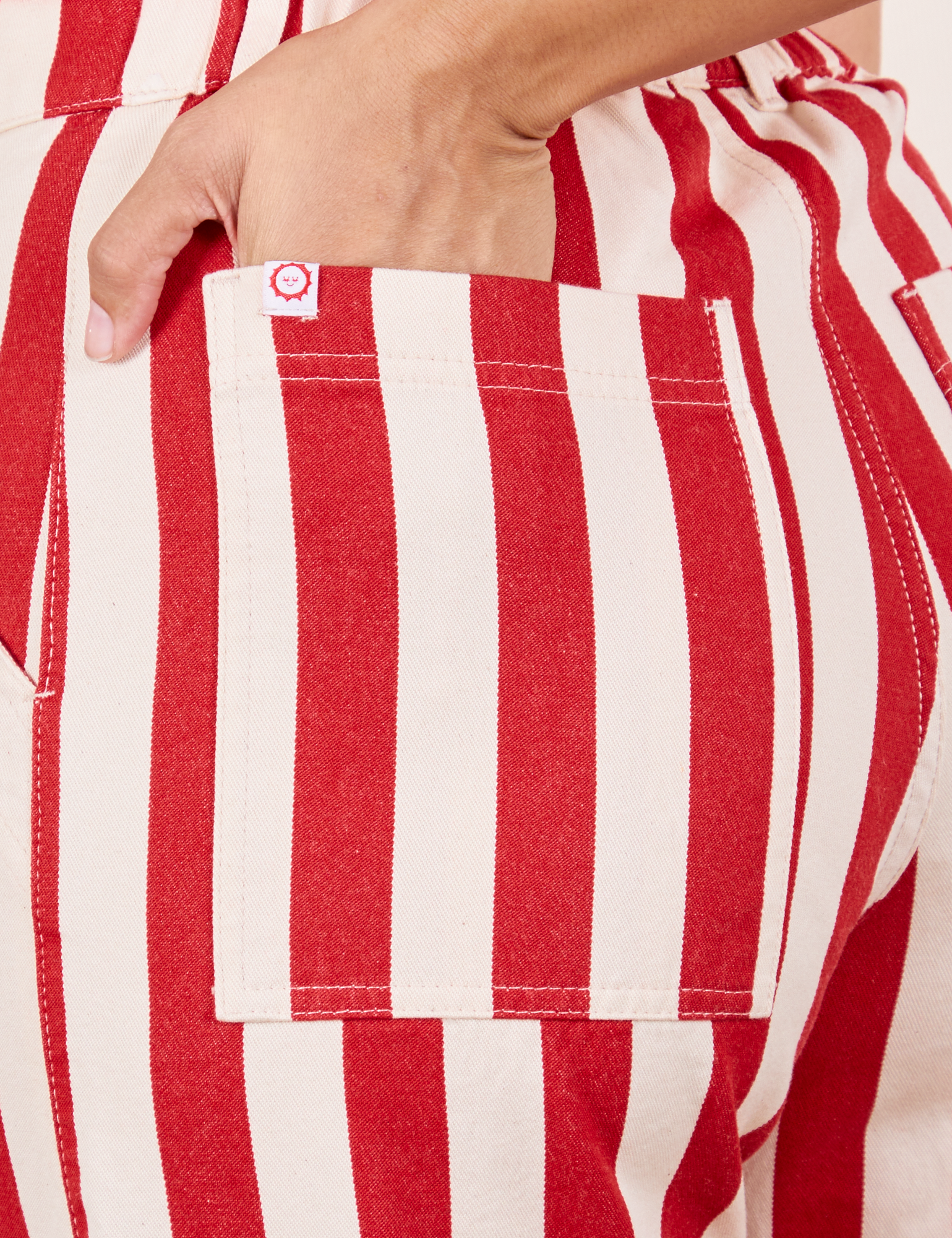 Work Pants in Cherry Stripe back pocket close up. Tiara has her hand in the pocket.
