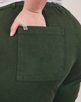 Work Pants in Swamp Green back pocket close up. Marielena has her hand in the pocket.