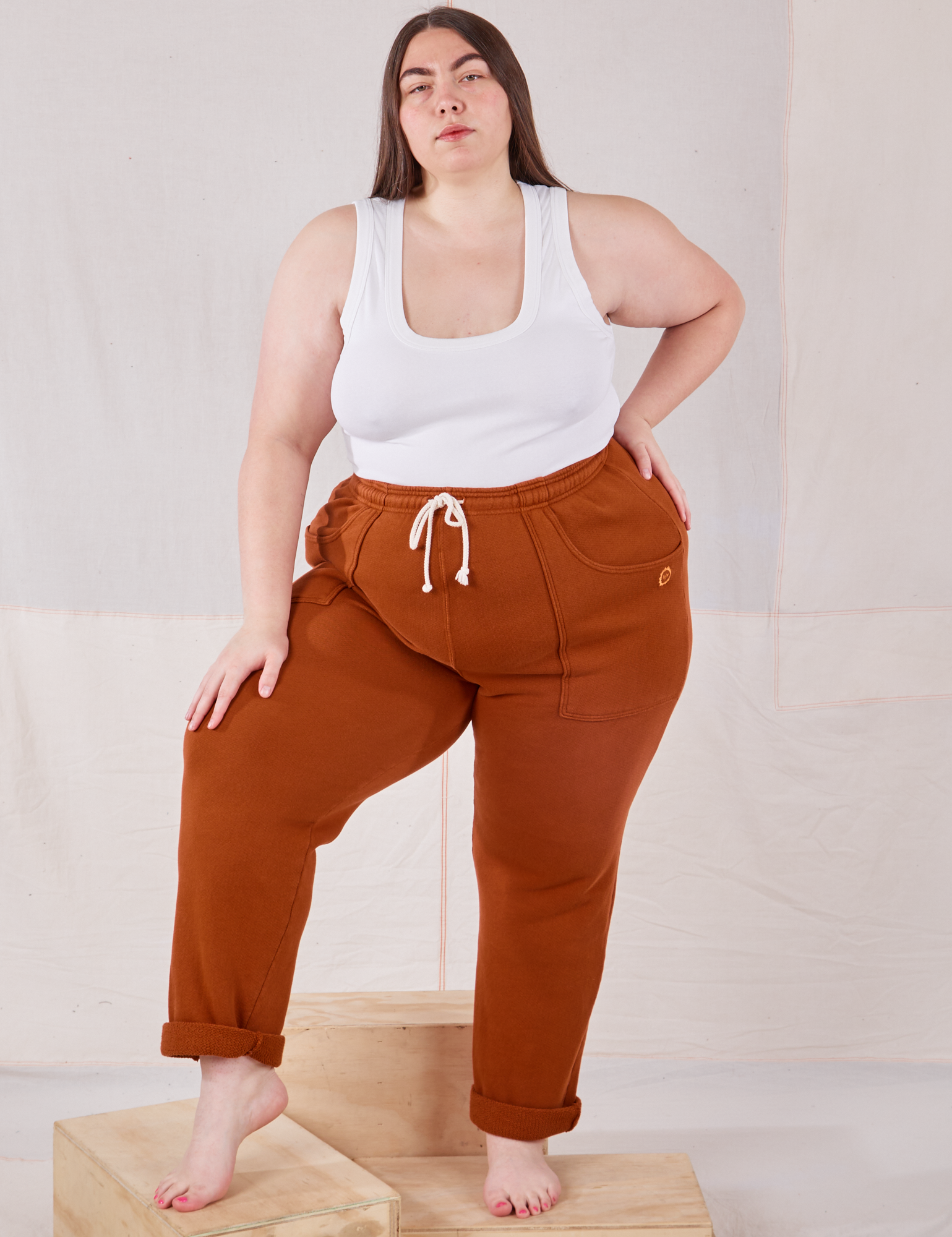 Marielena is 5&#39;8&quot; and wearing 1XL Rolled Cuff Sweat Pants in Burnt Terracotta paired with Cropped Tank in vintage tee off-white