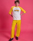 Quinn is wearing Taxi Raglan Tee in Toronto and golden yellow Western Pants