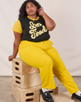 Anniversary Tee in I’m Tired and golden yellow Work Pants worn by Morgan