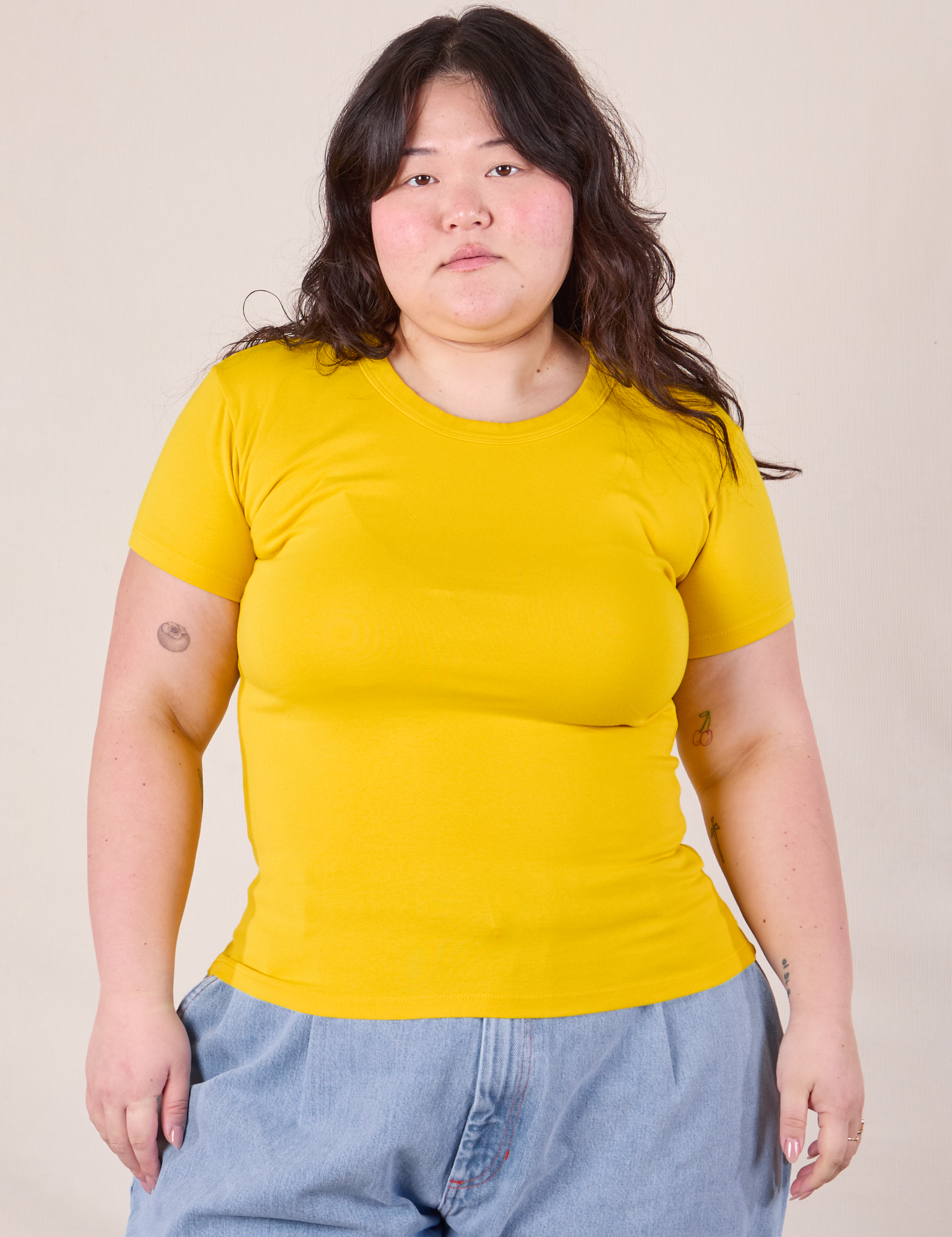 Ashley is 5'7" and wearing L Baby Tee in Golden Yellow
