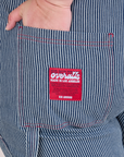 Close up of Ashley's hand in the back pocket of Carpenter Overalls in Railroad