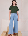 Alex is wearing Cropped Burly Tee in Swamp Green wide leg denim trousers in light wash