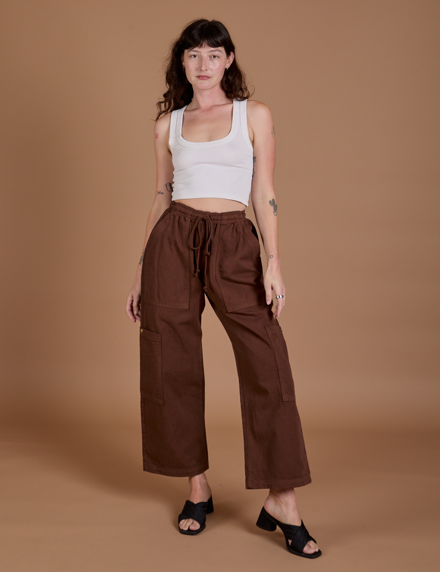 Alex is 5’8” and wearing XXS Drop Pocket Cargo Pants in Fudgesicle  Brown paired with a Cropped Tank in vintage tee white