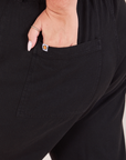 Heritage Short Sleeve Jumpsuit in Basic Black back pocket close up. Katie has her hand in the pocket.