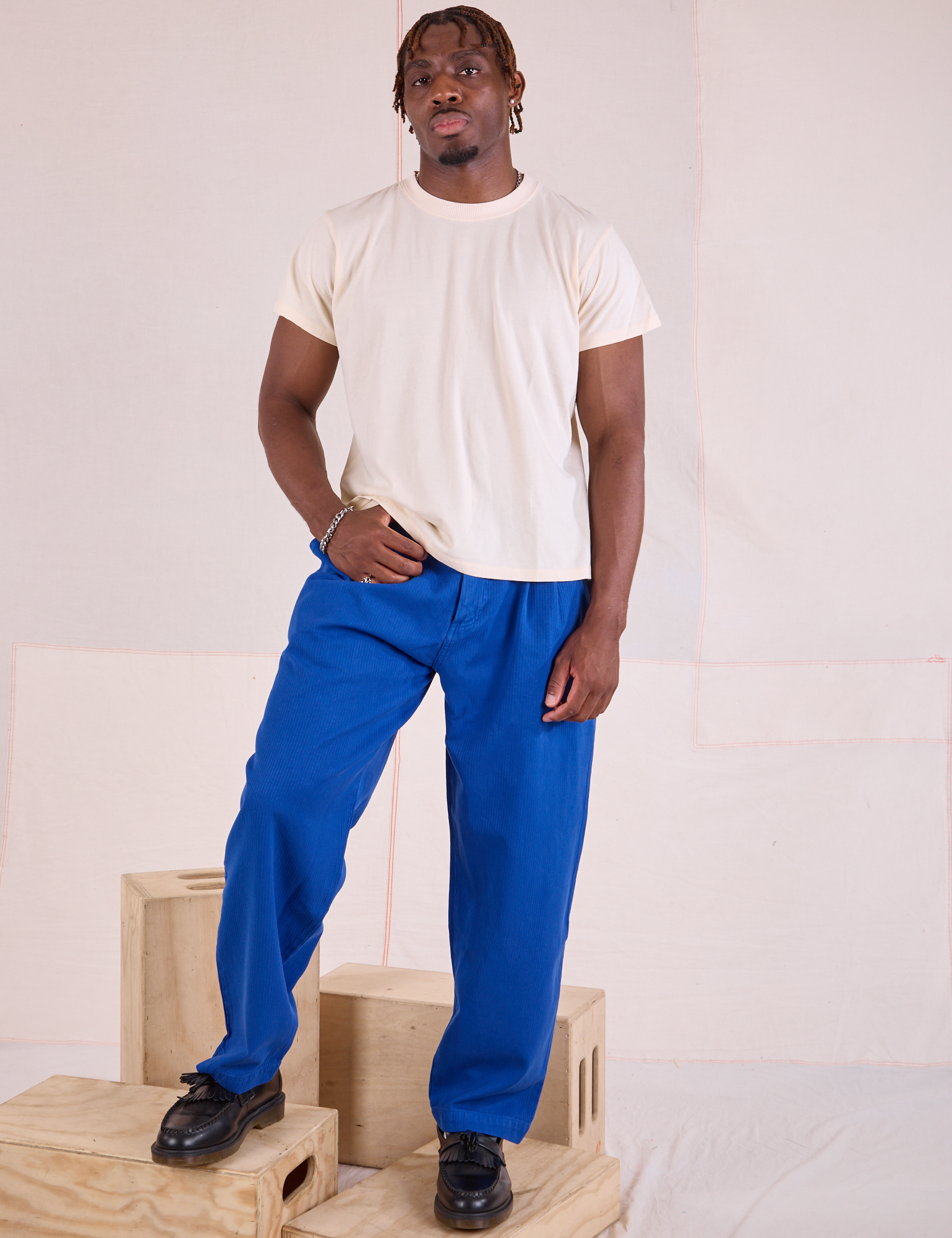 Issac 5’10” is and wearing M Heritage Trousers in Royal Blue paired with an Organic Vintage Tee in vintage tee off-white