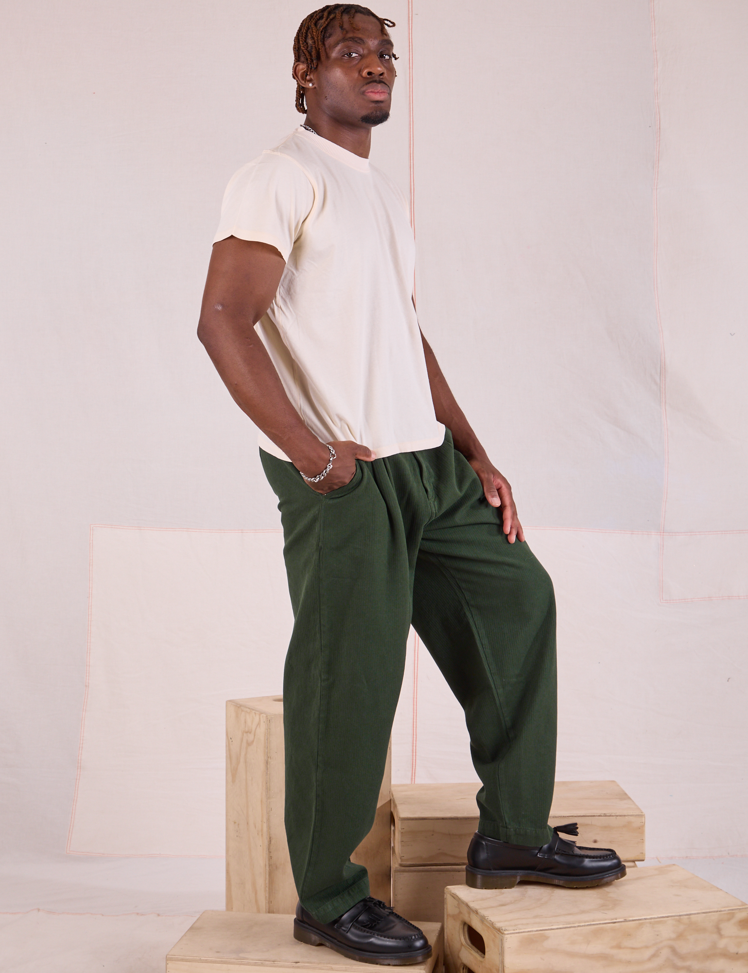 Side view of Heritage Trousers in Swamp Green and Organic Vintage Tee in vintage tee off-white on Issac