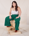 Ashley is wearing Bell Bottoms in Hunter Green and Halter Top in vintage tee off-white sitting on a wooden crate.