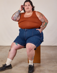 Sam is wearing Carpenter Shorts in Dark Wash and burnt terracotta Cropped Tank