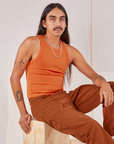 Anthony is wearing Racerback Tank in Sunset Orange and burnt terracotta Western Pants