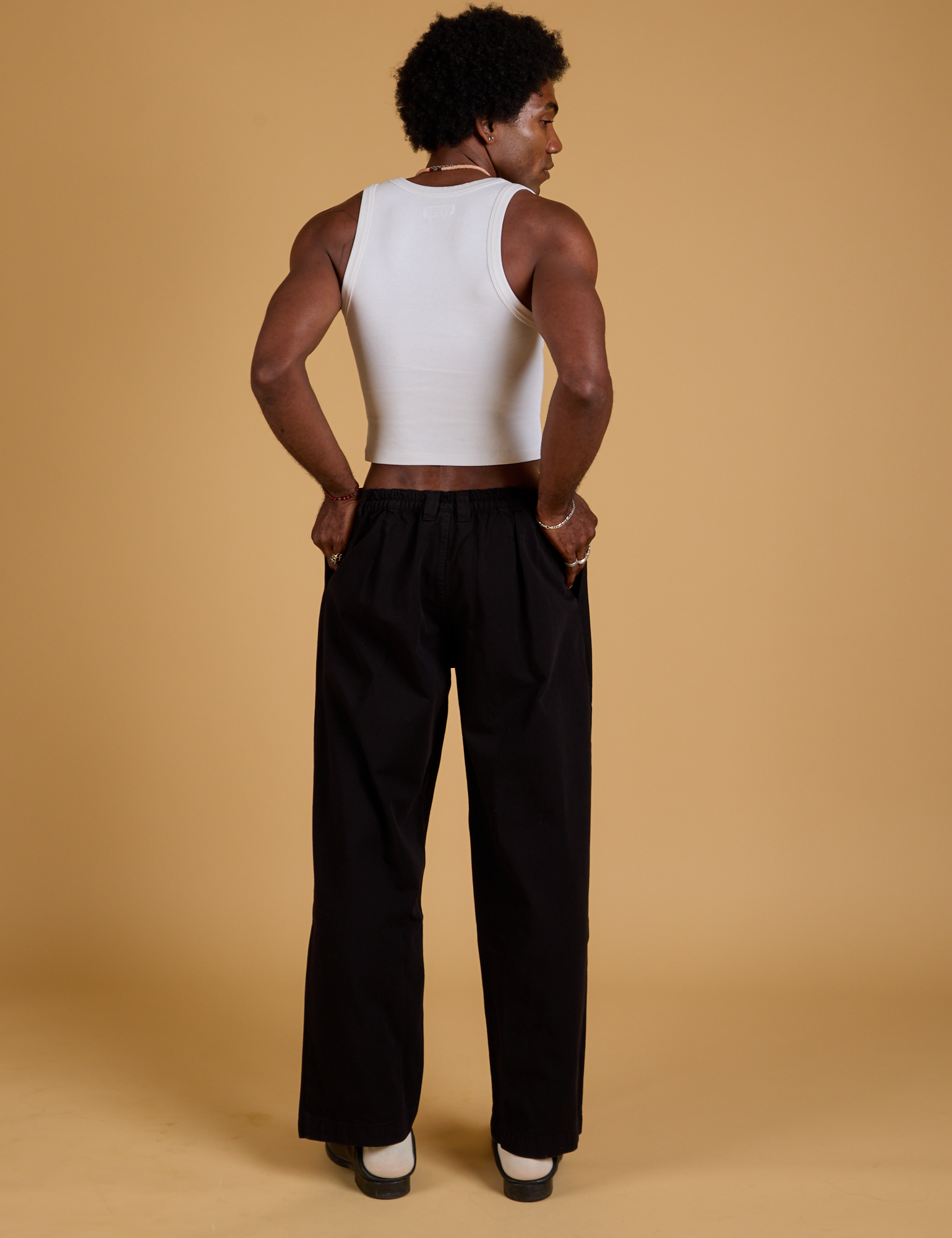 Back view of Baggy Mid-Rise Trousers in Basic Black and vintage tee white Cropped Tank on Jerrod