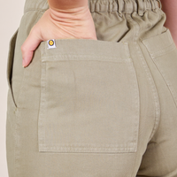 Back pocket close up of Short Sleeve Jumpsuit in Khaki Grey. Alex has her hand in the pocket.