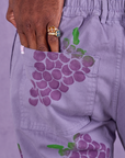 Close up of Jerrod's hand tucked into the back pocket of Paintstamped Work Pants in Grape