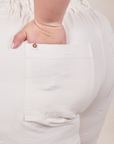 Back pocket close up of Short Sleeve Jumpsuit in Vintage Tee Off-White. Ashley has her hand in the pocket.