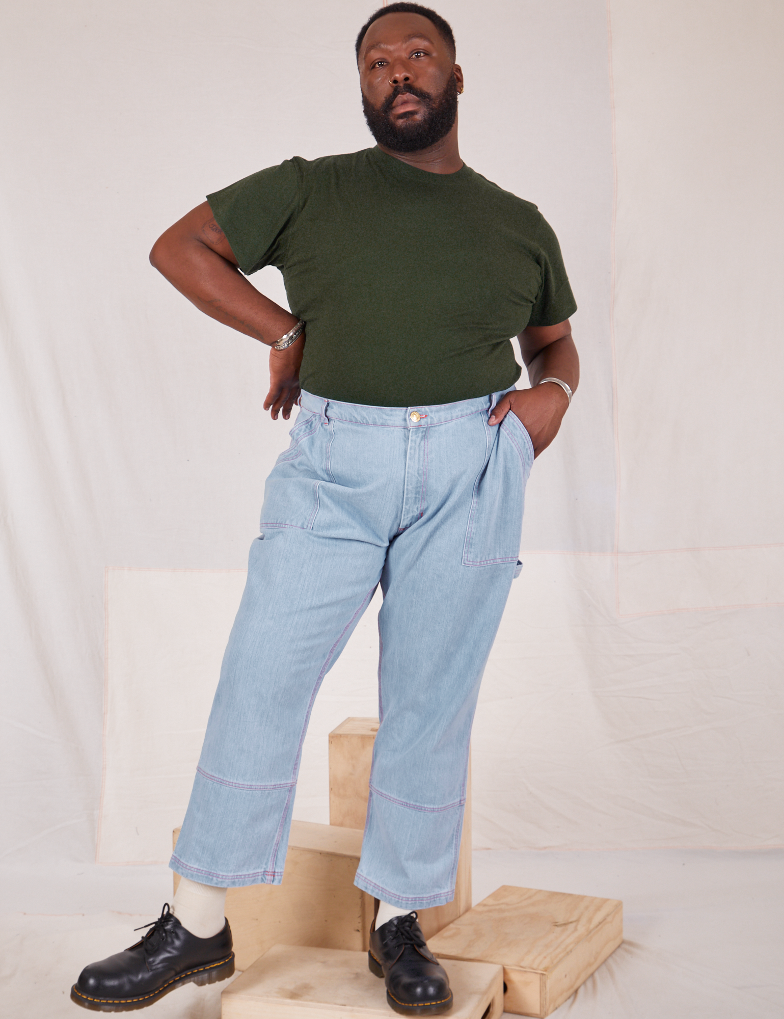 Elijah is wearing Organic Vintage Tee in Swamp Green tucked into light wash Carpenter Jeans