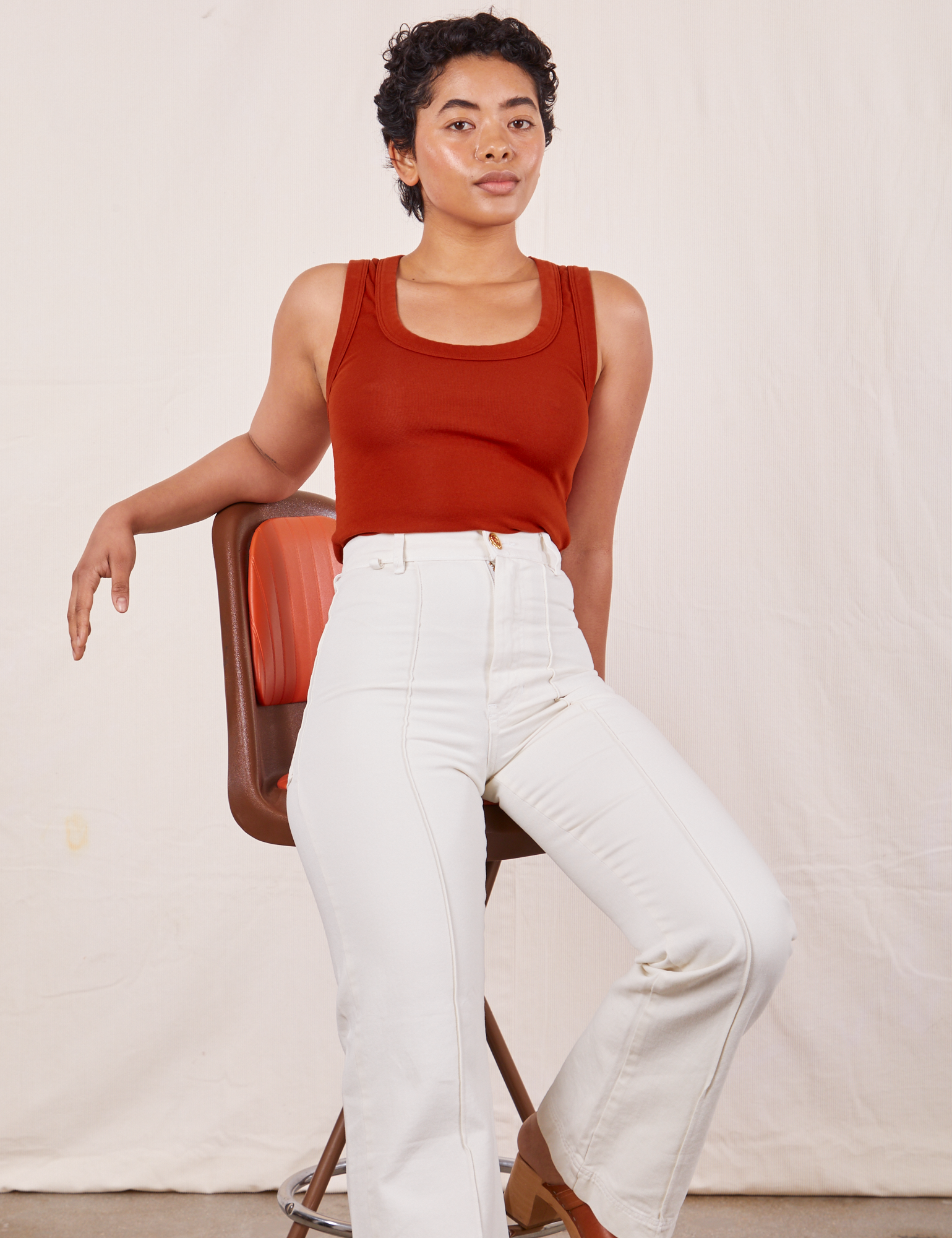 Mika sitting on vintage bar stool wearing Tank Top in Paprika and vintage tee off-white Western Pants