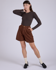 Alex is 5’8” and wearing XXS Pleated Trouser Shorts in Fudgesicle Brown paired with espresso brown Long Sleeve Baby Tee