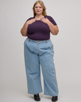 Juliet is wearing Baby Tee in Nebula Purple tucked into light wash wide leg trousers