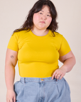 Ashley is wearing Baby Tee in Golden Yellow tucked into denim Trousers