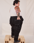 Angled back view of Carpenter Jeans in Black and Tank Top in vintage tee off-white worn by Sam