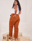 Angled back view of Carpenter Jeans in Burnt Terracotta on Meghna
