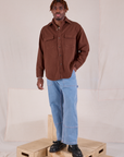 Isaac is wearing Flannel Overshirt in Fudgesicle Brown and light wash Carpenter Jeans