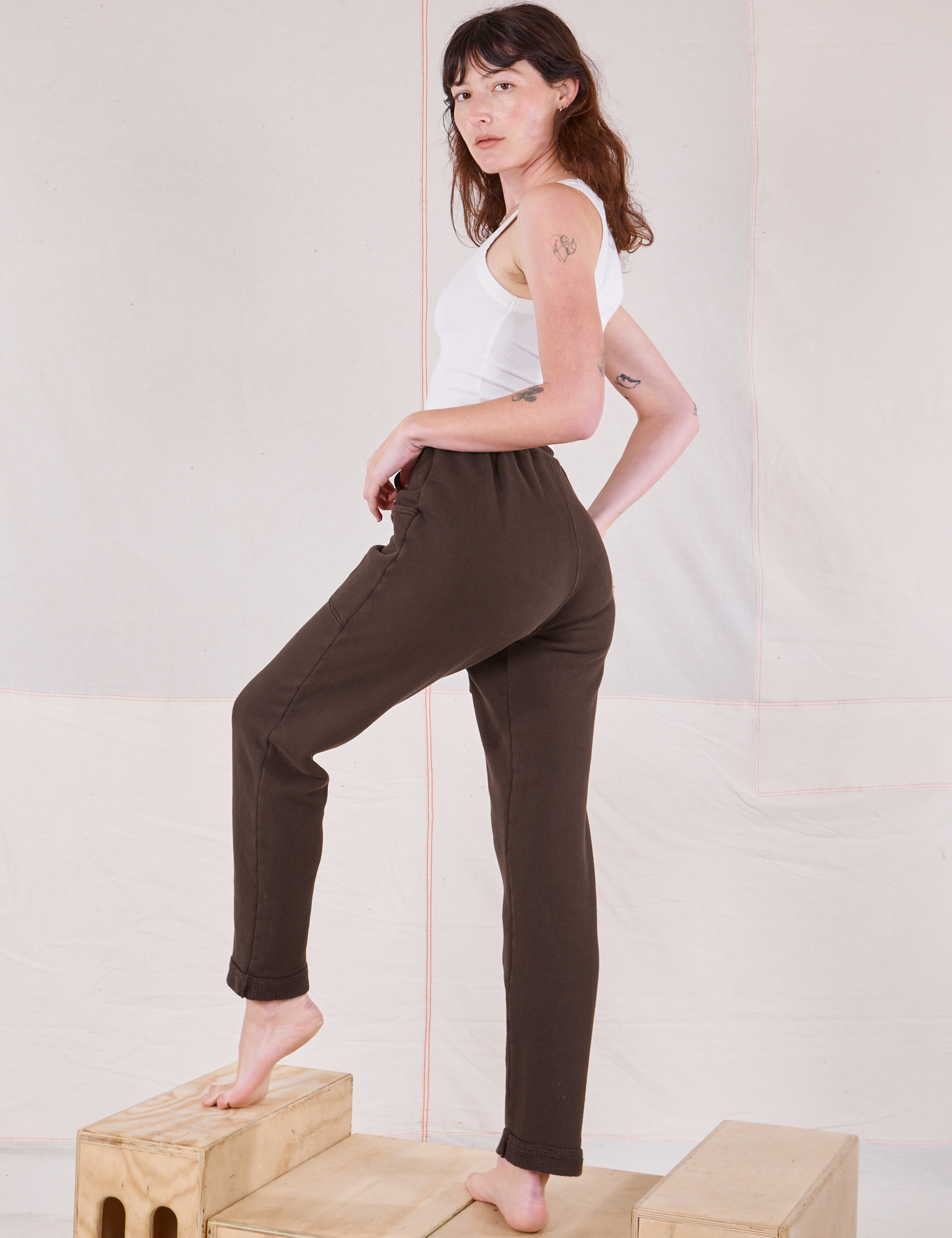 Angled back view of Rolled Cuff Sweat Pants in Espresso Brown and Cropped Tank in vintage tee off-white on Alex