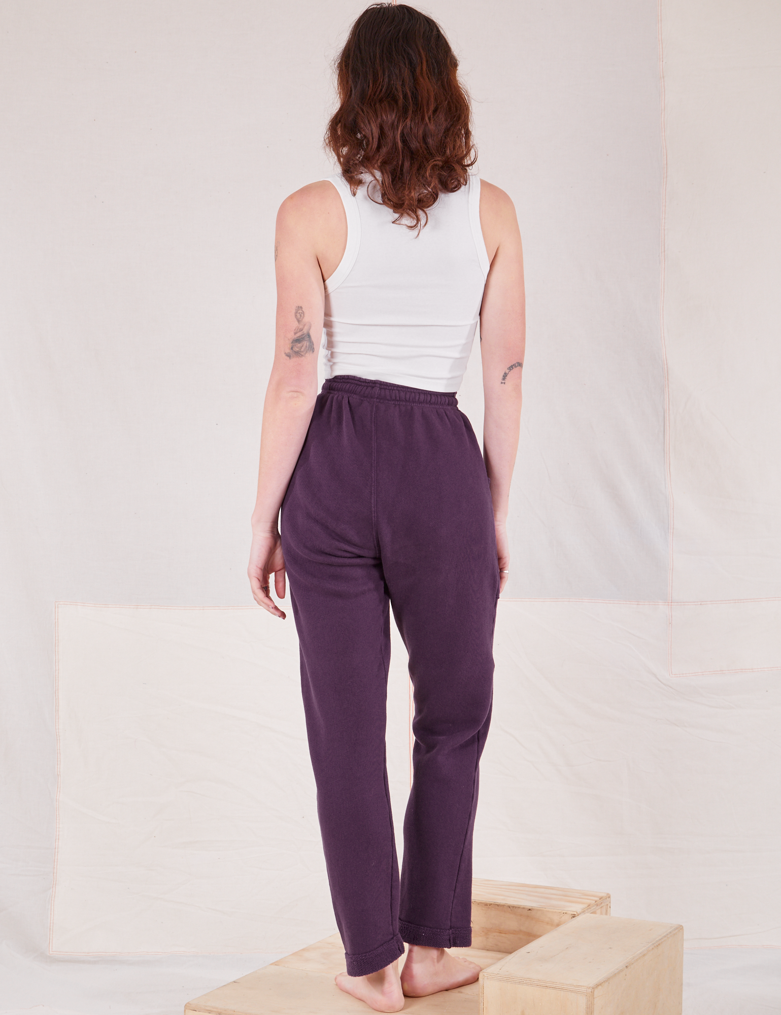 Back view of Rolled Cuff Sweat Pants in Nebula Purple and Cropped Tank in vintage tee off-white on Alex