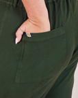 Heritage Short Sleeve Jumpsuit in Swamp Green back pocket close up. Katie has her hand in the pocket.