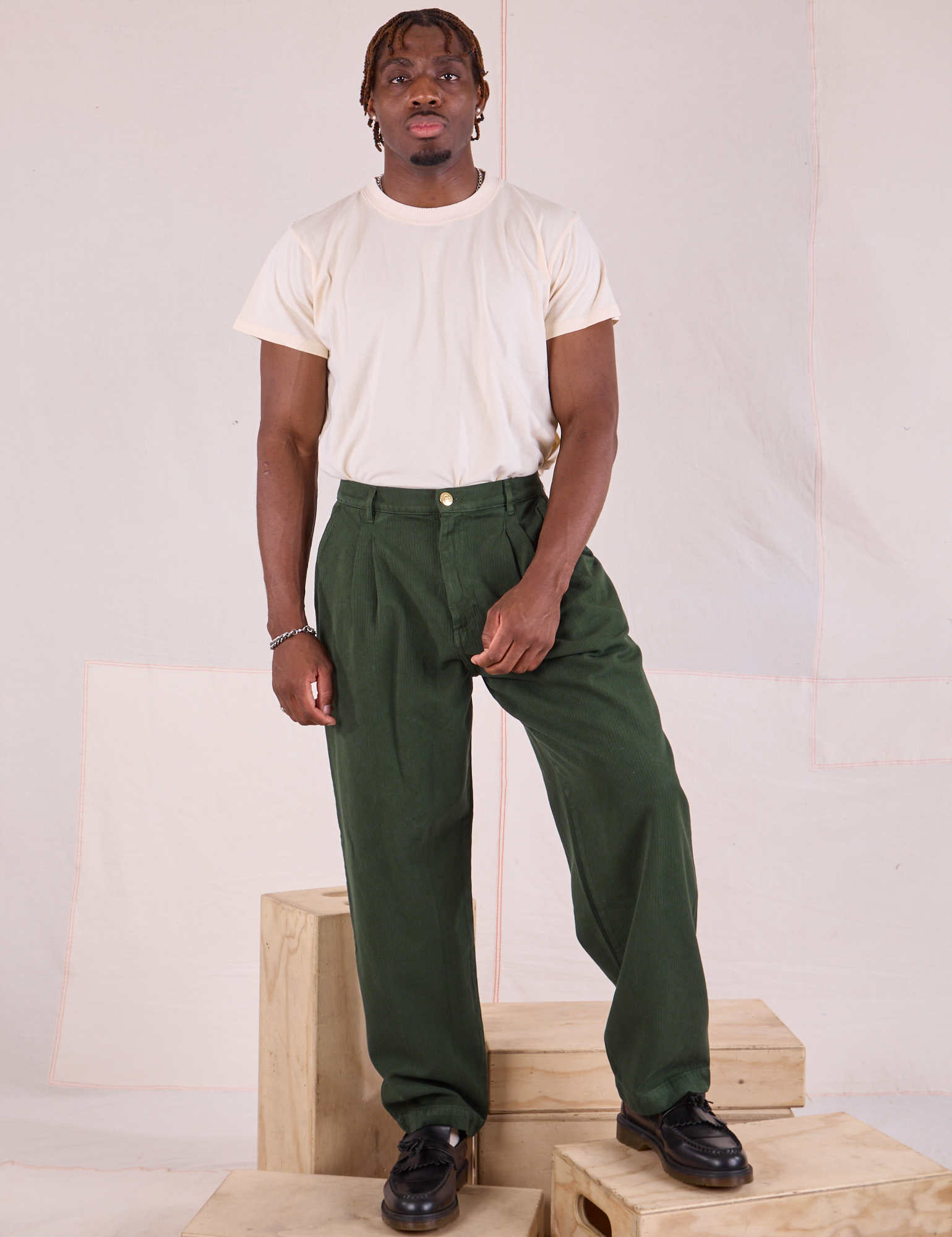 Issac is wearing Heritage Trousers in Swamp Green and Organic Vintage Tee in vintage tee off-white