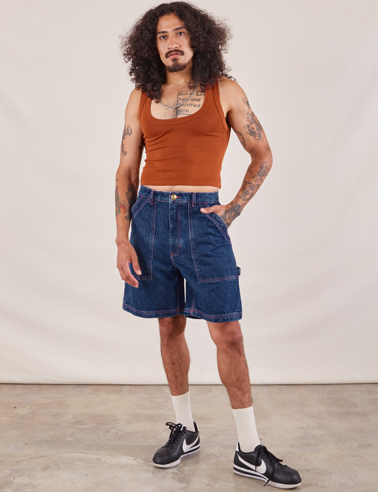 Jesse is 5'8" and wearing S Carpenter Shorts in Dark Wash paired with a burnt terracotta Cropped Tank