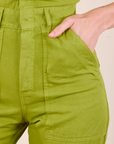 Short Sleeve Jumpsuit in Gross Green front pocket close up. Alex has her hand in the pocket.
